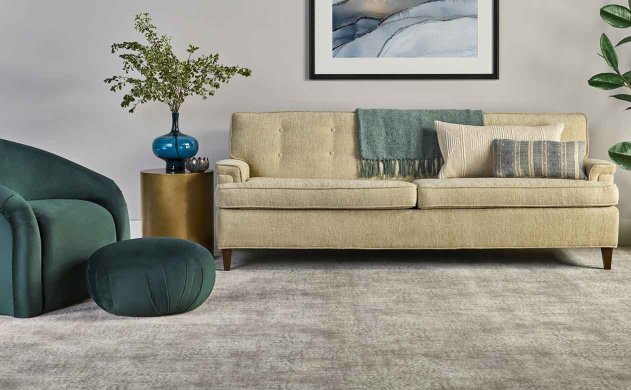 Grey carpet in living room with beige and green furniture
